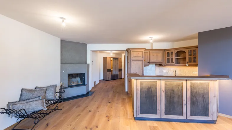 Offener Wohnbereich mit Kamin, Holzboden und integrierter Bar/Küchenzeile in modernem Design.