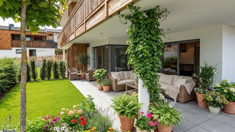 Eine einladende Terrasse mit bequemen Gartenmöbeln, umgeben von einem gepflegten Rasen und bunten Blumenbeeten.