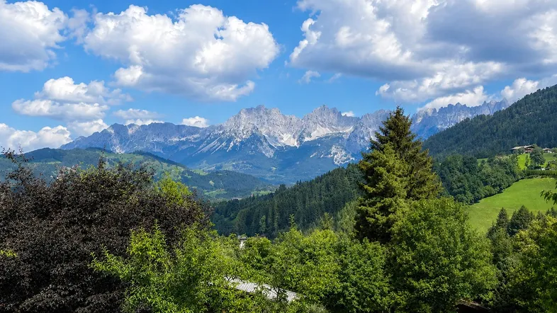 Panoramablick auf die majestätischen Berge und die umliegende grüne Landschaft unter blauem Himmel.