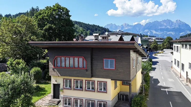 Hausfassade mit traditionellen Holzelementen und Blick auf die umliegende Berglandschaft.