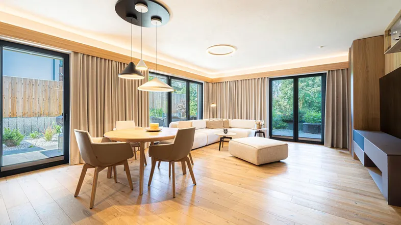 Heller, offener Wohn- und Essbereich mit Holzboden, großen Fenstern und modernem Design.