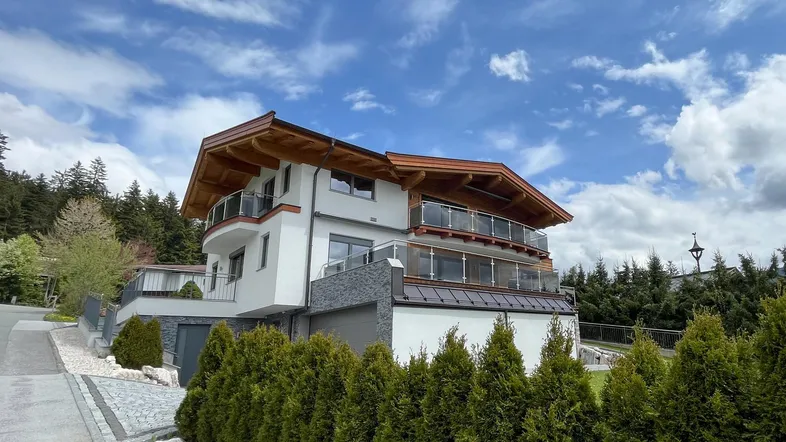 Moderne Architektur mit Holzverkleidung und mehreren Balkonen unter bewölktem Himmel.