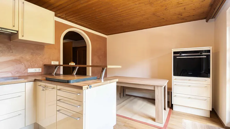 Helle Küche mit Holzdecke, integriertem Backofen und Esstisch für gemütliche Mahlzeiten.