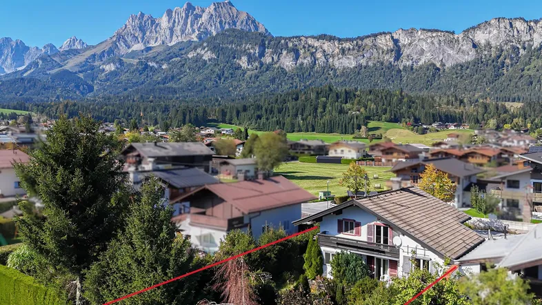 Luftaufnahme eines Hauses mit Bergblick und umgebender Natur in sonniger Lage.