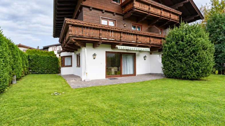 Traditionelles Holzhaus mit weißer Fassade, kleiner Terrasse und gepflegtem Rasenbereich.