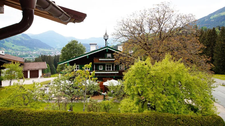Traditionelles Haus im Alpenstil mit Blick auf die umliegende Berglandschaft und grüne Hügel.