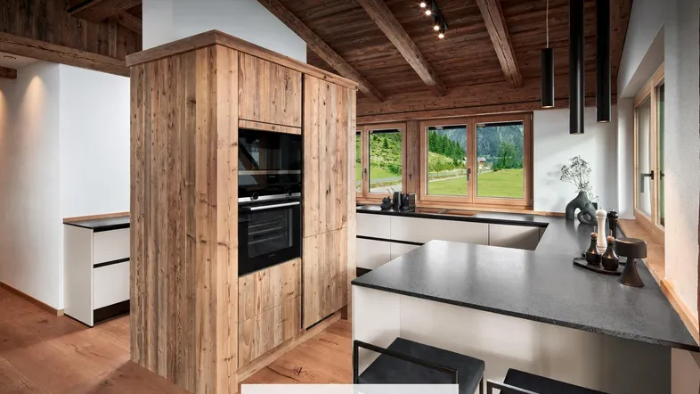 Moderne Küche im alpinen Stil mit Holzelementen, Einbaugeräten und Blick ins Grüne.