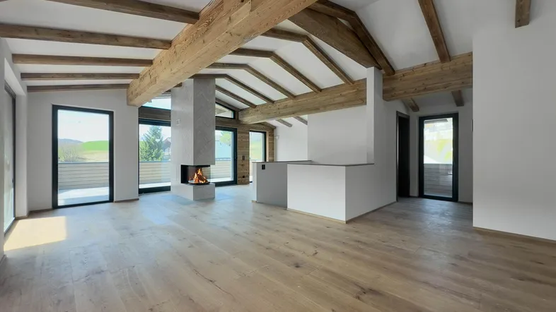 Helles Wohnzimmer mit Holzbalken, Kamin und Zugang zu mehreren Balkonen, bietet viel natürliches Licht.