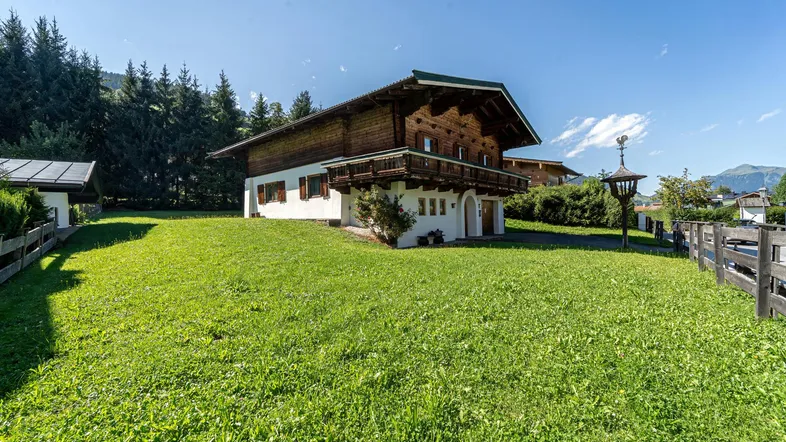Traditionelles Haus im alpenländischen Stil mit großem Garten und Blick auf die umliegende Berglandschaft.