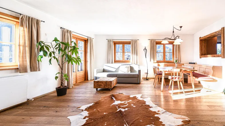 Heller, offener Wohn- und Essbereich mit Holzboden, gemütlichem Sofa und Esstisch.