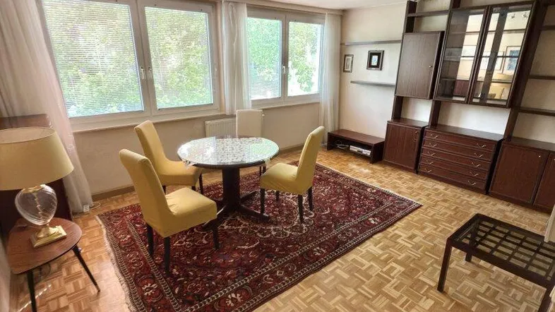Gemütliches Wohnzimmer mit Parkettboden, einem runden Esstisch und einer traditionellen Schrankwand.