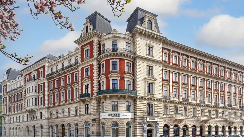 Großes, historisches Gebäude mit eleganter Architektur und blühenden Magnolien im Vordergrund.