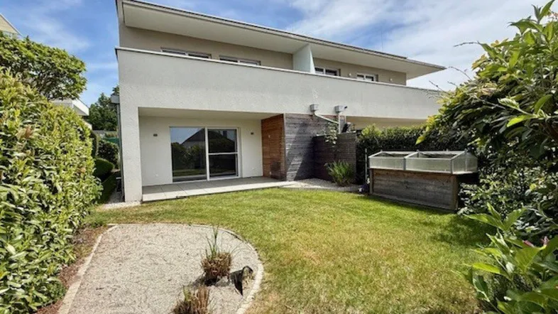 Moderne Wohnanlage mit gepflegtem Gartenbereich und kleiner Terrasse im Erdgeschoss.