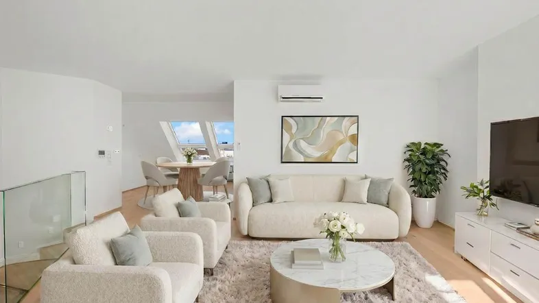 Helles, modern eingerichtetes Wohn-Esszimmer mit bequemen Sofas, Teppich und einem Essbereich im Hintergrund.