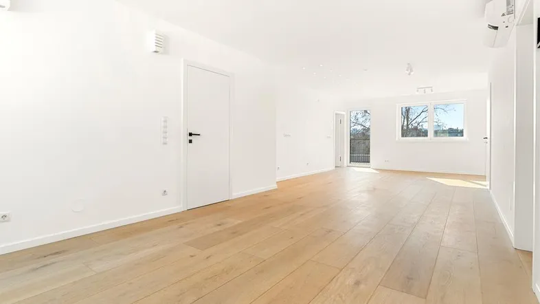 Heller, geräumiger Wohnbereich mit Eichenparkett und weißen Wänden, bereit zum Einzug.