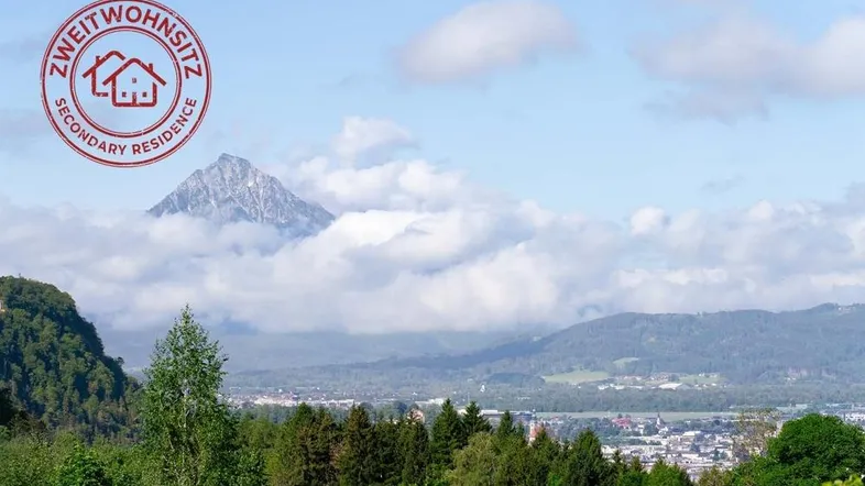 Panoramablick auf die majestätischen Berge und das Tal mit einer Stadt im Hintergrund.