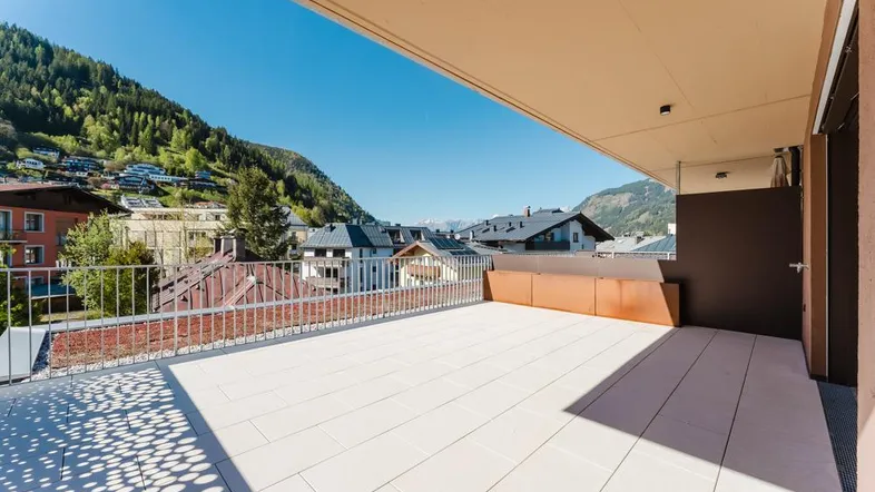 Geräumige Terrasse mit Fliesenboden und weitem Blick auf die umliegende Berglandschaft.