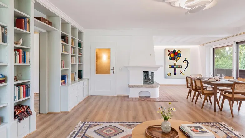 Helles Wohn- und Esszimmer mit Kamin, Parkettboden und Zugang zum Balkon.