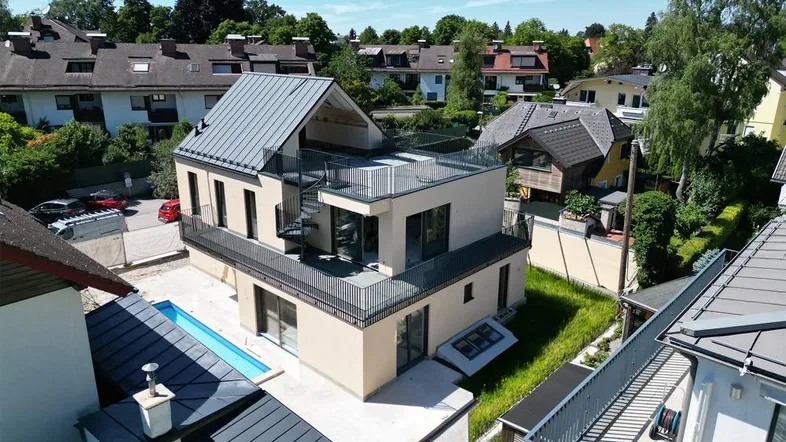 Moderne Villa mit Flachdach, Pool und Dachterrasse in grüner Umgebung.