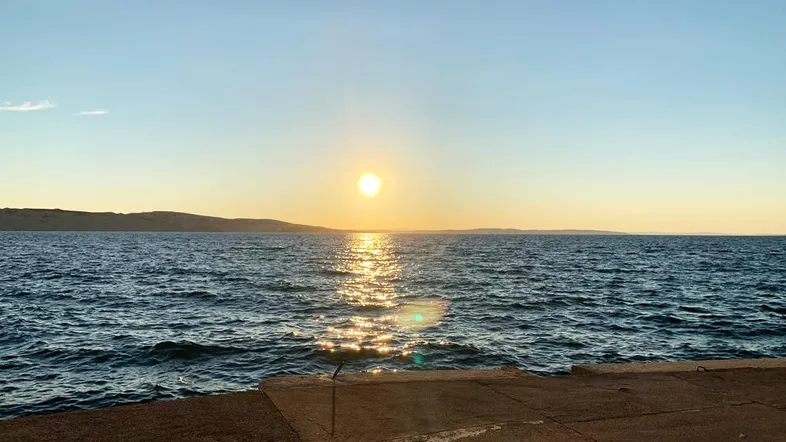 Sonnenuntergang über dem Meer mit glitzerndem Wasser und weitem Horizont.