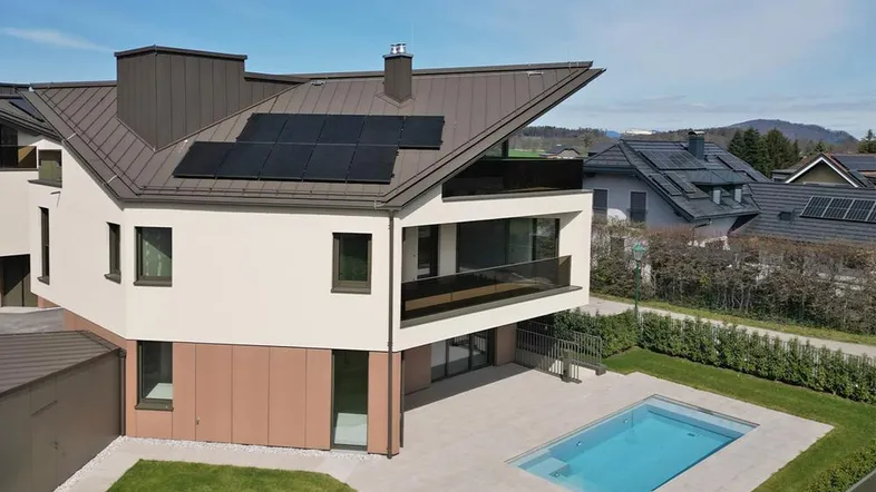 Modernes Gebäude mit Photovoltaikanlage auf dem Dach und einem privaten Pool im Gartenbereich.