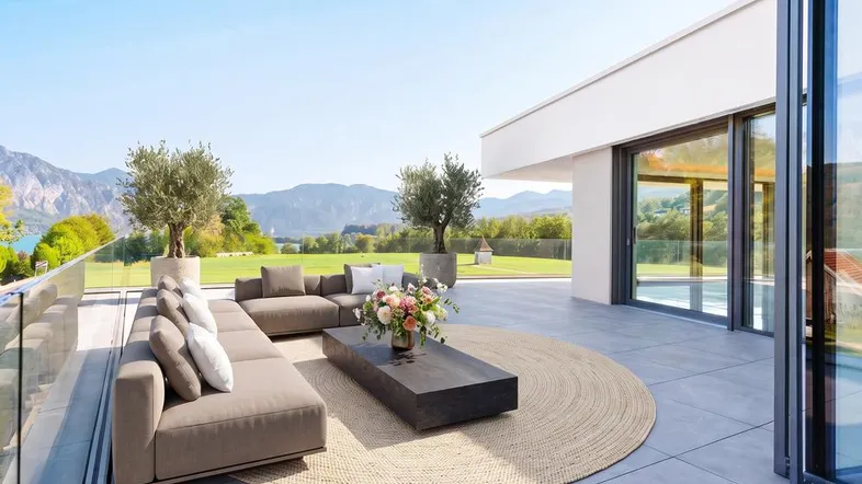 Moderne Terrasse mit bequemen Loungemöbeln und Panoramablick auf See und Berge.
