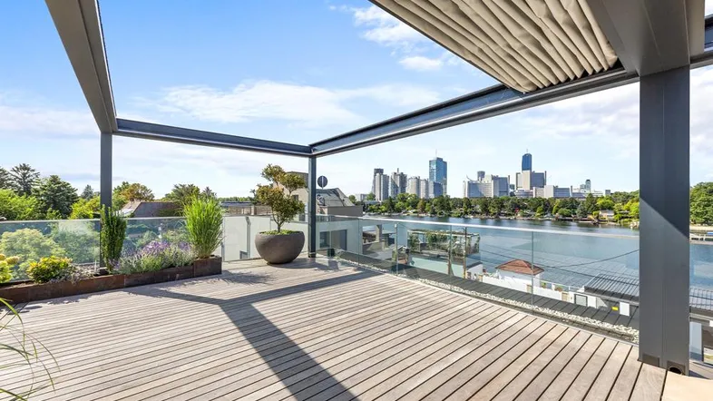 Geräumige Dachterrasse mit Holzboden, Pergola und beeindruckendem Blick auf die Stadt und den See.