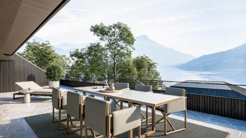 Geräumige Terrasse mit Esstisch und Liegestuhl, bietet einen atemberaubenden Blick auf den See und die Berge.