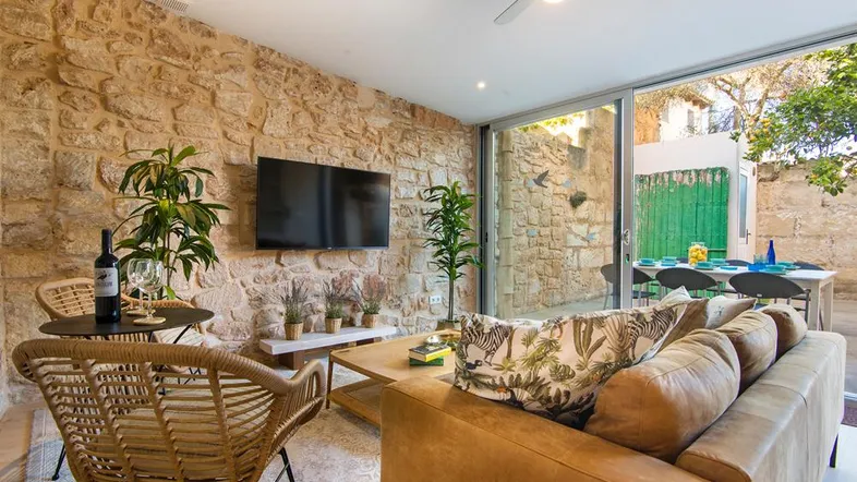 Gemütliches Wohnzimmer mit Natursteinwand, bequemer Couch und Zugang zur Außenterrasse.