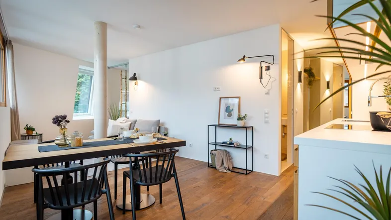 Heller, offener Wohn- und Essbereich mit Holzboden und moderner Einrichtung, ideal für geselliges Beisammensein.