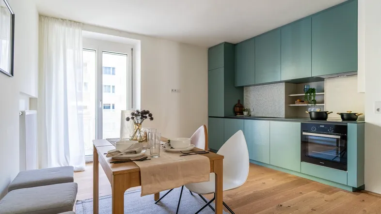 Helle, offene Küche mit mintgrünen Schränken und Essbereich, ideal für gemeinsame Mahlzeiten.