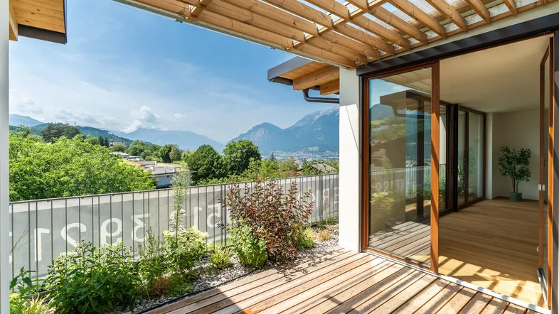 Große Holzterrasse mit Pergola, Pflanzen und weitem Blick auf die Berge und die umliegende Landschaft.