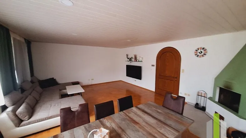 Geräumiger Wohn-Essbereich mit gemütlichem Sofa, rustikalem Esstisch und einem Kamin für kalte Tage.