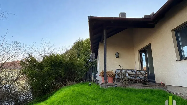 Überdachte Terrasse mit gemütlichen Sitzgelegenheiten und Blick auf den grünen Gartenbereich.