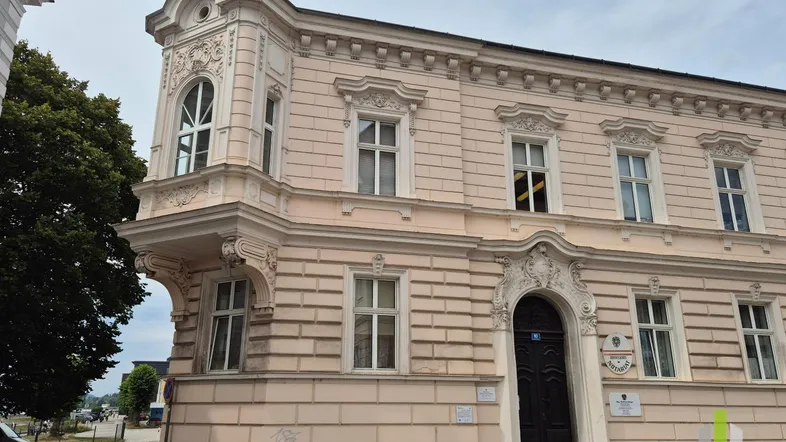 Historisches Gebäude mit aufwendiger Fassadenverzierung und Eck-Erker in hellem Rosaton.