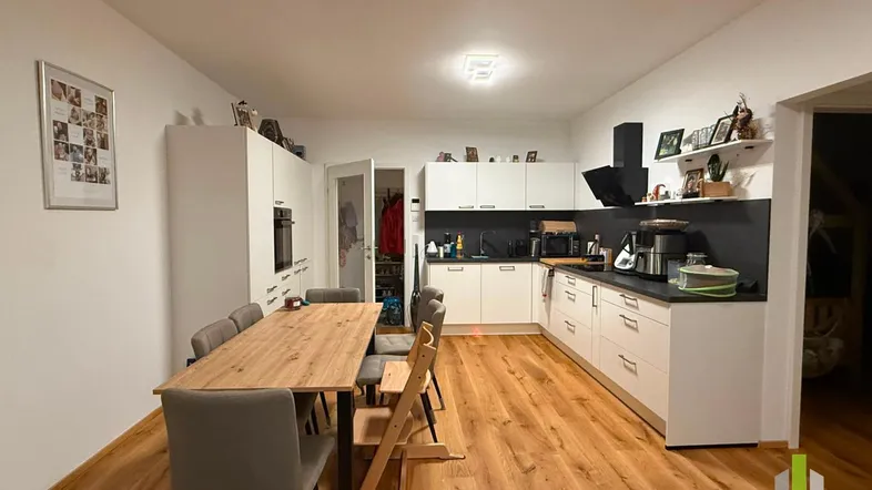Moderne Küche mit weißen Schränken, Holzboden und integriertem Essbereich für die Familie.