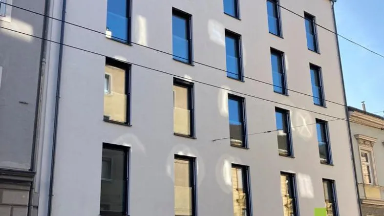 Moderne Fassade eines Neubaus mit vielen Fenstern und klaren Linien in städtischer Umgebung.