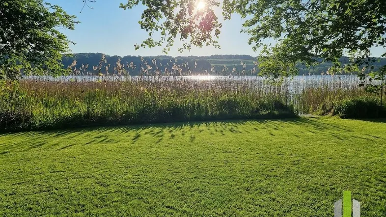 Gepflegter Rasenbereich mit direktem Zugang zum See und sonnigem Blick auf das Wasser.