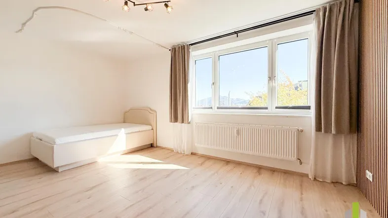 Helles Schlafzimmer mit modernem Holzlattenwand-Akzent, großem Fenster und hellem Laminatboden.