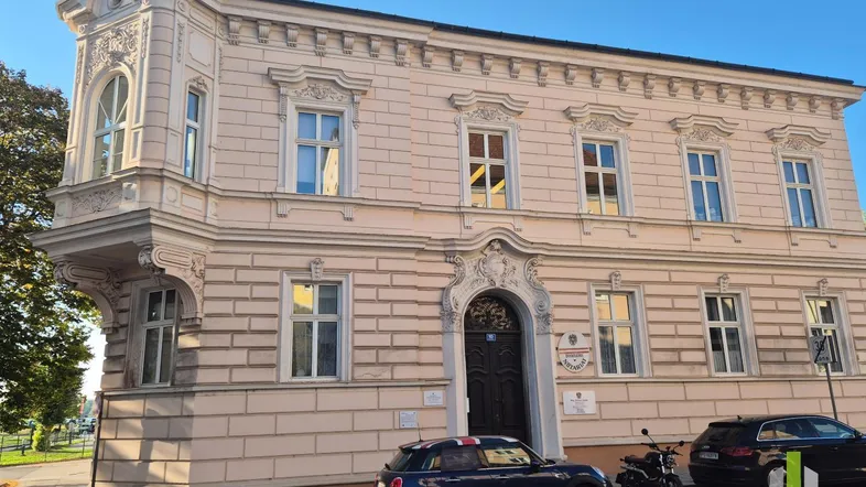 Historisches Gebäude mit aufwendiger Fassadenverzierung und Erker in einer städtischen Umgebung.