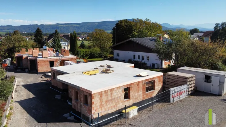 Luftaufnahme einer Baustelle mit mehreren im Bau befindlichen Häusern und ländlicher Umgebung.