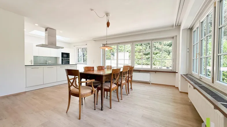 Helles, offenes Wohn- und Esszimmer mit integrierter Küche und großen Fenstern.