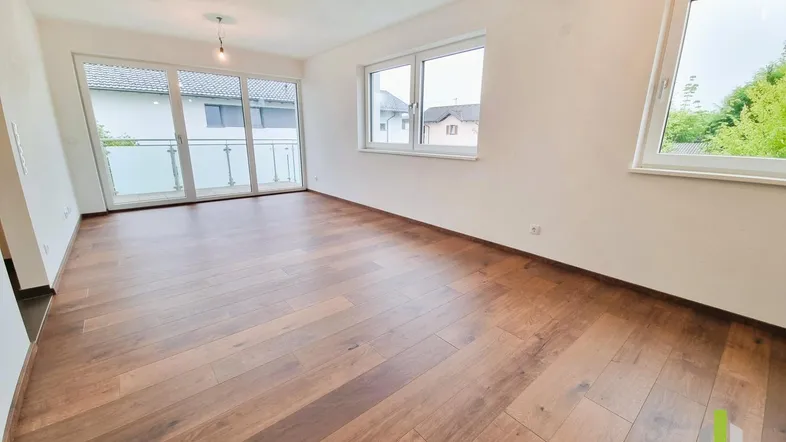 Helles, leeres Wohnzimmer mit Holzboden und Zugang zu einem Balkon, ideal für individuelle Gestaltung.