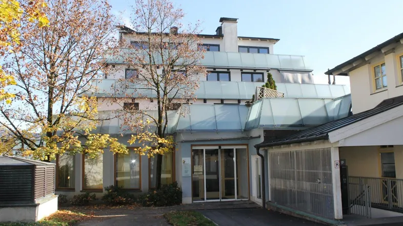 Gebäudeansicht mit gestufter Architektur, Glasgeländern und Eingangsbereich mit automatischen Türen.