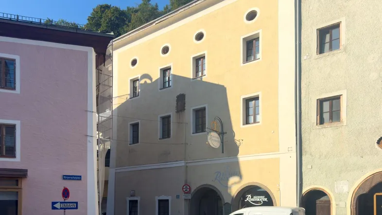 Historisches Gebäude mit gelber Fassade, runden Fenstern und einem Geschäft im Erdgeschoss.