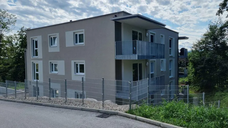 Modernes Mehrfamilienhaus mit mehreren Balkonen und gepflegter Außenanlage in grüner Umgebung.