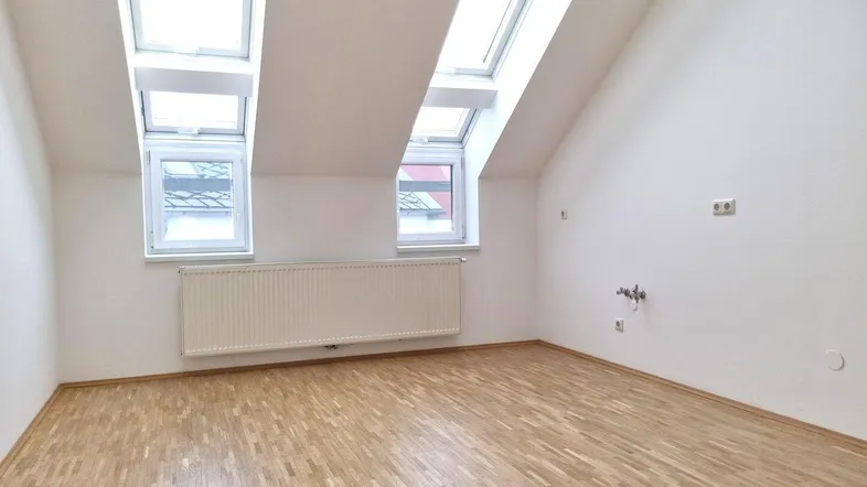Geräumiges Dachzimmer mit viel Tageslicht durch mehrere Dach- und Giebelfenster.