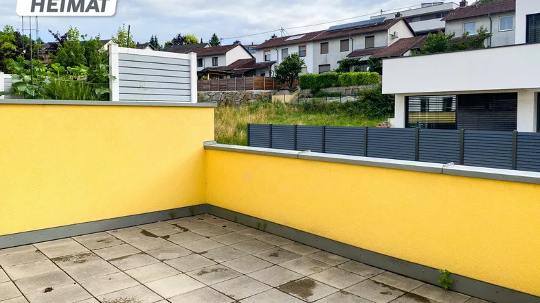 Geräumige Terrasse mit gelber Brüstung und Blick auf die umliegende Wohnsiedlung.
