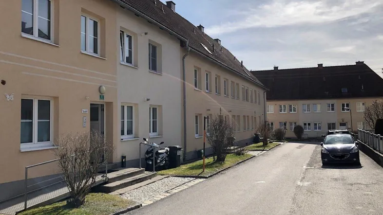 Wohngebäude mit mehreren Einheiten entlang einer ruhigen Straße unter bewölktem Himmel.