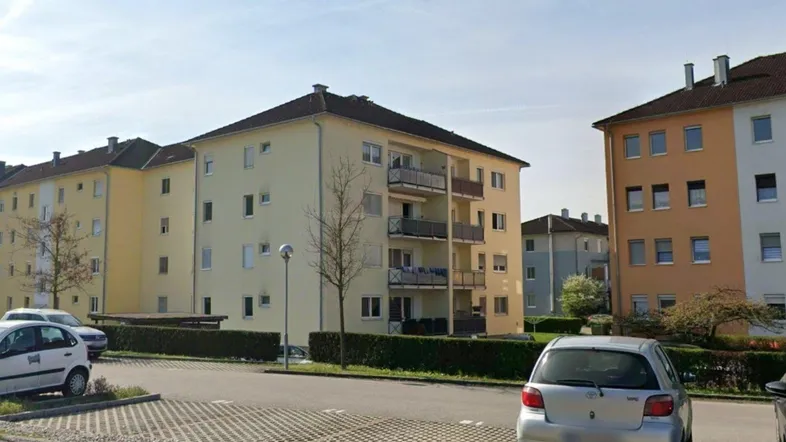 Mehrere Wohngebäude mit gelben Fassaden, Balkonen und gepflegten Hecken in einer Wohnsiedlung.